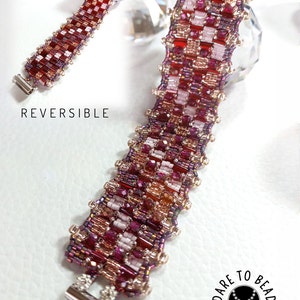 May include: A reversible beaded bracelet with a checkered pattern in shades of red, pink, and white. The bracelet is made with small glass beads and has silver-toned clasps. The text "REVERSIBLE" is visible in the image. The text "DARE TO BEAD" is also visible in the image, along with the text "heather laithwaite - designs."
