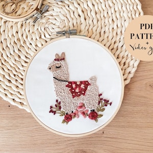 May include: A white embroidery hoop with a brown llama with a red and white saddle and red flowers. The text "PDF PATTERN + Video guide" is on a tan circle in the upper right corner of the image.