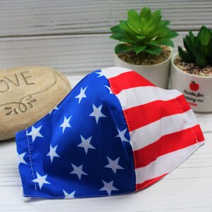 May include: A blue and red face mask with a stars and stripes pattern. The mask is made of fabric and has a white background.