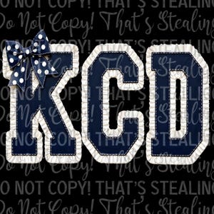May include: The letters K, C, and D in a dark navy blue color with a white stitched border and a ruffled white trim edge. A dark navy blue bow with white polka dots is attached to the top left corner of the letter K on a black background.
