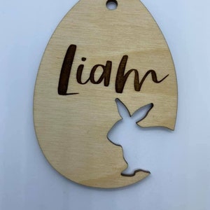 May include: A wooden Easter egg ornament with a bunny cutout and the name "Liam" engraved on it.