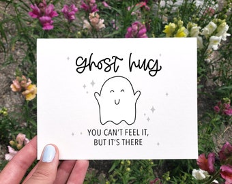 May include: A white card with a black line drawing of a ghost with a smiling face and the text "ghost hug" above the ghost and "You can't feel it, but it's there" below the ghost.