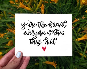 Puede incluir: Una tarjeta blanca con caligrafía negra que dice "eres el amigo que todos desean tener" y un pequeño corazón rojo en el centro inferior.