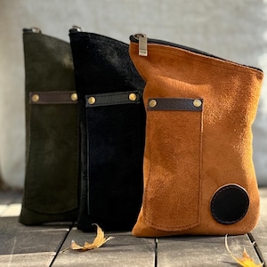 Pode incluir: Três bolsas de camurça em verde-oliva, preto e castanho claro, cada uma com zíper e um pequeno bolso. As bolsas têm formato retangular com cantos arredondados e são decoradas com detalhes em couro e rebites de latão.