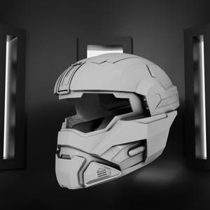 May include: A gray, futuristic-style helmet with a visor opening and detailed facial protection. The helmet has a complex design with various panels and ridges, suggesting a high-tech or sci-fi theme. The helmet is set against a dark background.