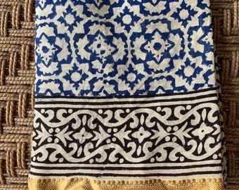 May include: A white cotton square scarf with a blue and black geometric pattern. The scarf has a gold trim around the edges.