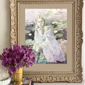 May include: A framed watercolor painting depicts a person in a white dress seated near water lilies. The painting is in a decorative, ornate, gold-toned frame. A bouquet of purple flowers in a gold vase and books are in the foreground.