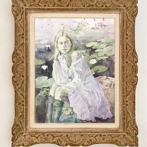 May include: Watercolor painting in a decorative gold frame. The artwork depicts a woman in a white dress seated among lily pads. The frame has ornate detailing. The painting has a soft, ethereal quality with muted colors.