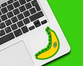 May include: A yellow banana sticker with a green border and a white oval. The sticker is on a laptop and features the text "na-na-na" and "bu-nu-nu" in green around the banana.