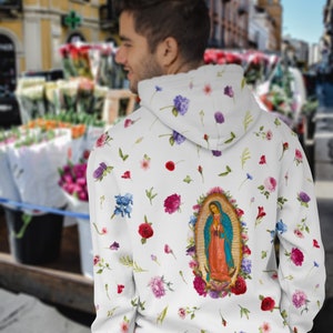 May include: White hoodie with a floral print and a large image of Our Lady of Guadalupe on the back.