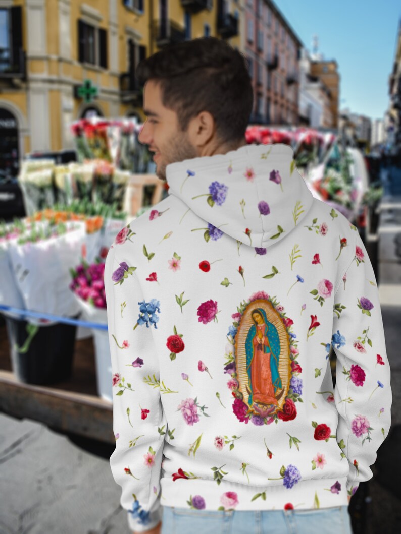 May include: White hoodie with a floral print and a large image of Our Lady of Guadalupe on the back.