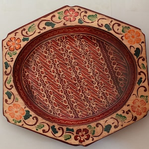 Könnte beinhalten: Ein sechseckiges Serviertablett aus Holz mit einem roten, orangefarbenen und grünen Blumendesign. Das Tablett hat einen erhöhten Rand und eine glatte, polierte Oberfläche.