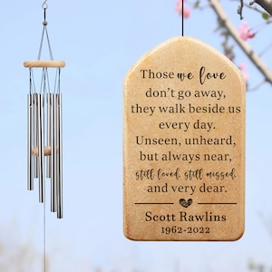 May include: A beige wooden wind chime with a heart and the text "Those we love don't go away, they walk beside us every day. Unseen, unheard, but always near, still loved, still missed, and very dear. Scott Rawlins 1962-2022"