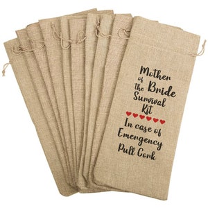 May include: A collection of beige burlap wine bottle bags with drawstring closures. The bags are printed with the text "Mother of the Bride Survival Kit" and "In case of Emergency Pull Cork" with red heart accents.