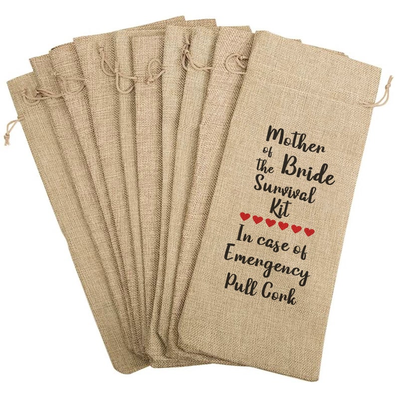 May include: A collection of beige burlap wine bottle bags with drawstring closures. The bags are printed with the text "Mother of the Bride Survival Kit" and "In case of Emergency Pull Cork" with red heart accents.
