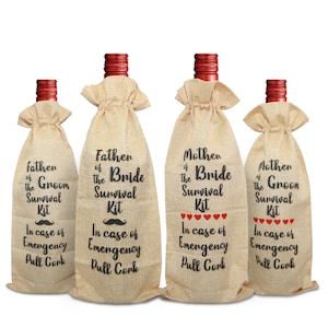 May include: Four wine bottle gift bags made of burlap. Each bag has a red bottle top and is labeled with black text: "Father of the Groom Survival Kit", "Father of the Bride Survival Kit", "Mother of the Bride Survival Kit", and "Mother of the Groom Survival Kit".
