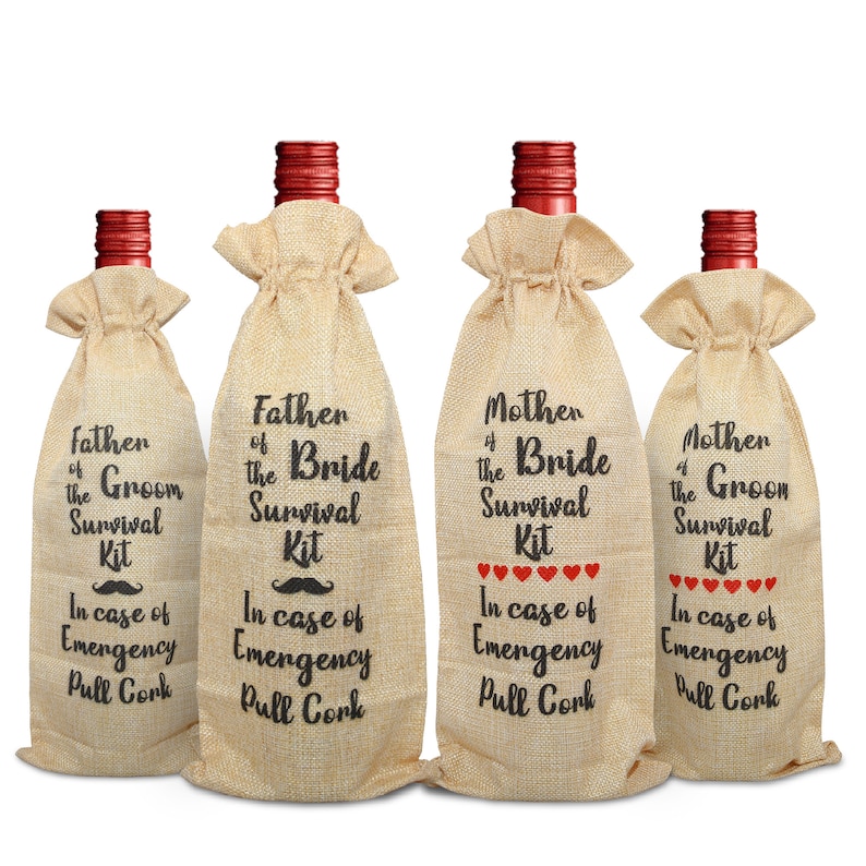 May include: Four wine bottle gift bags made of burlap. Each bag has a red bottle top and is labeled with black text: "Father of the Groom Survival Kit", "Father of the Bride Survival Kit", "Mother of the Bride Survival Kit", and "Mother of the Groom Survival Kit".