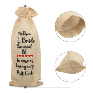 May include: A beige burlap wine bottle bag with a drawstring closure. The bag features the text "Mother of the Bride Survival Kit" in black, with red heart accents and the phrase "In case of Emergency Pull Cork."