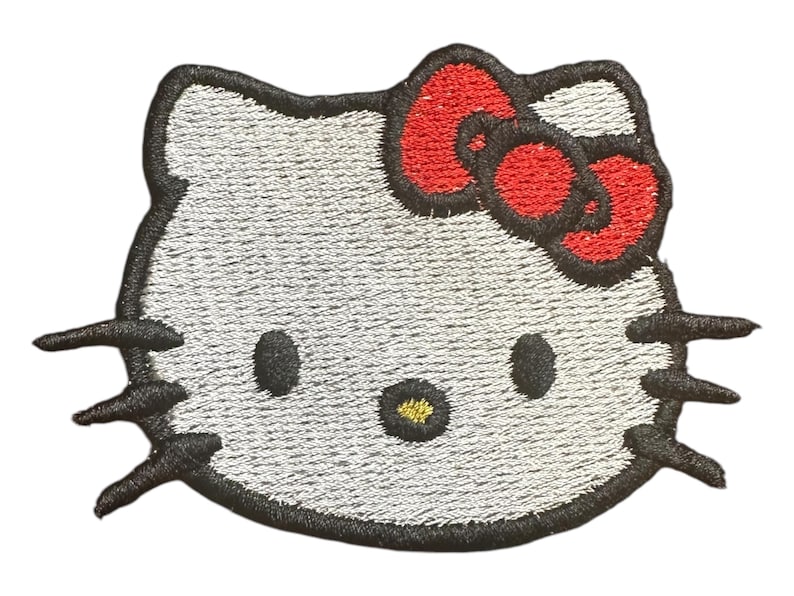 May include: A white embroidered iron-on patch of Hello Kitty with a red bow.