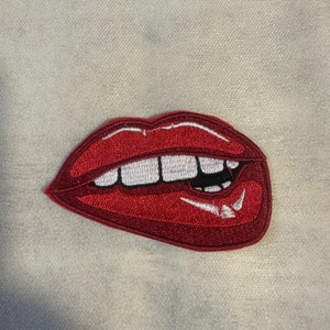 May include: Red embroidered lips with white teeth, a playful and bold design.