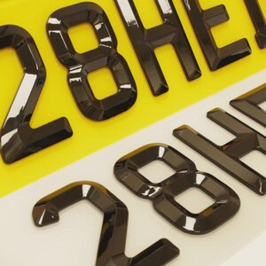 以下が含まれることがあります： 黒く光沢のある盛り上がった文字と数字が特徴のナンバープレートのクローズアップ。背景は黄色と白のセクションに分かれています。「28」の数字が目立っています。