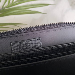 May include: Black zippered wallet with a black fabric lining and the text "L.L. Bean" printed on the inside.