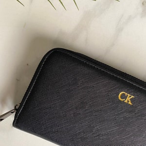 May include: Black leather zippered wallet with a gold CK logo.