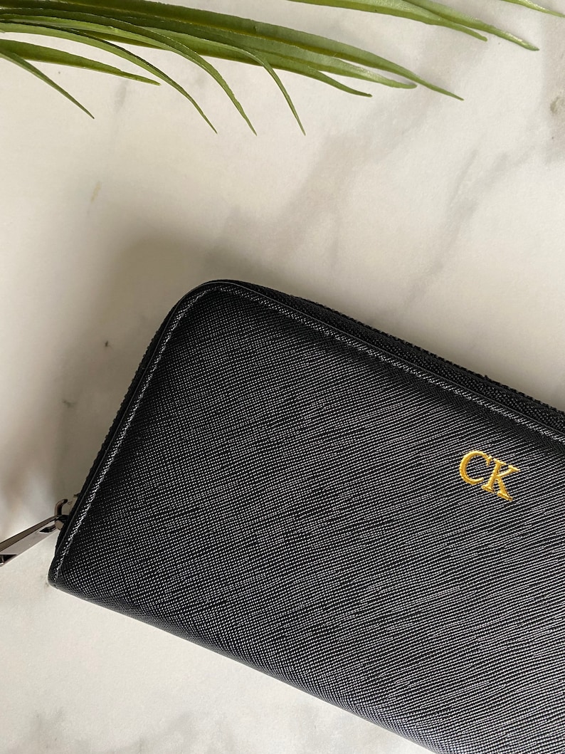 May include: Black leather zippered wallet with a gold CK logo.