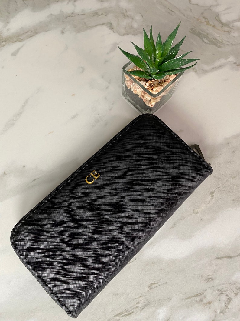 May include: A black leather zippered wallet with gold embossed initials "CB".