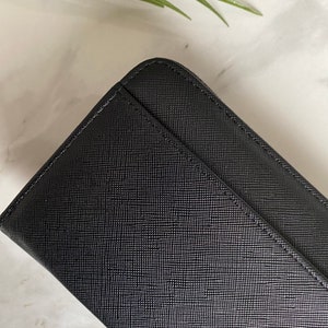 May include: Black leather wallet with a textured finish.