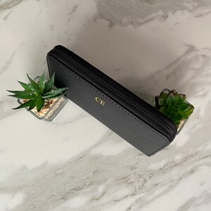May include: A black leather zippered wallet with gold lettering that says "CE".