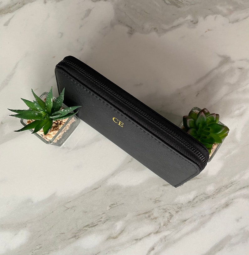 May include: A black leather zippered wallet with gold lettering that says "CE".