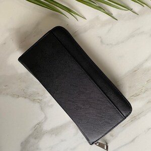 May include: A black leather zippered wallet with a textured surface.