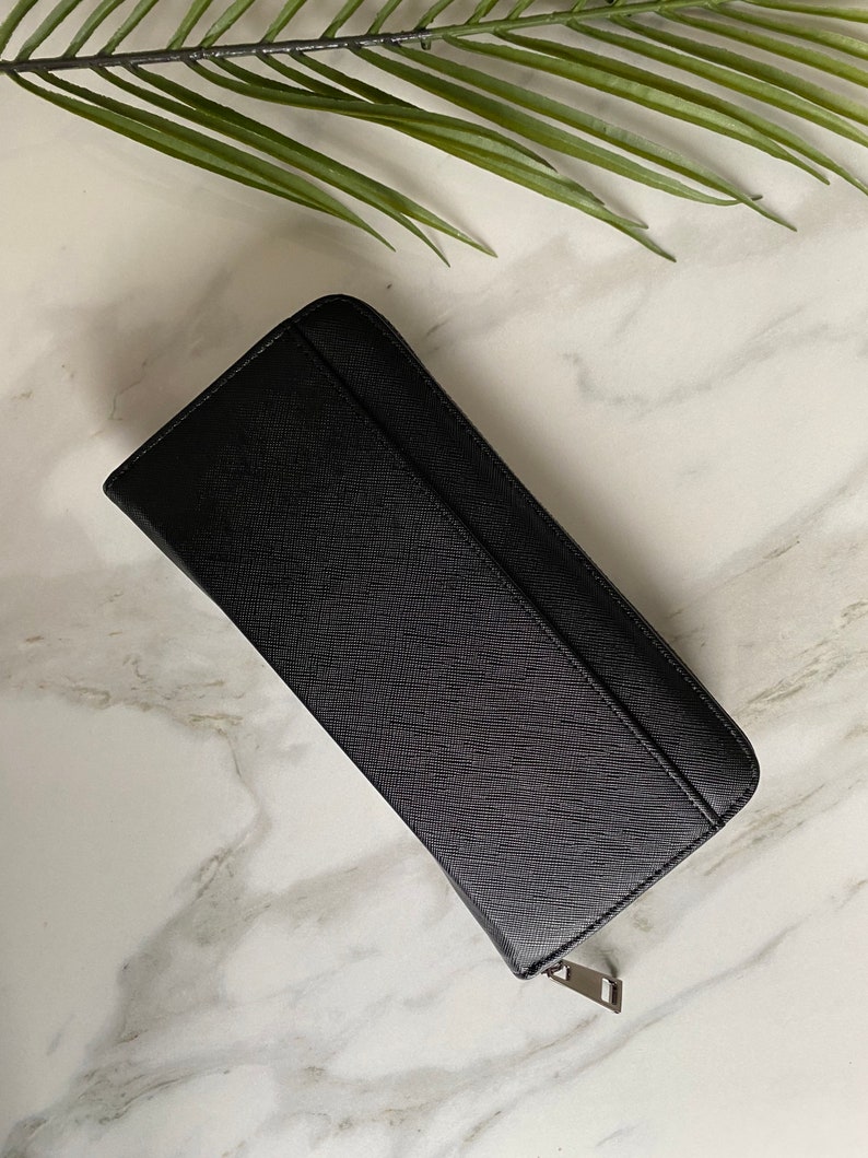 May include: A black leather zippered wallet with a textured surface.