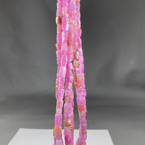 Può includere: Una collana di perle di rubino rosa, di forma quadrata, infilate su un filo d'argento. Le perle sono disposte in una lunga e fluida collana.