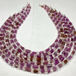 May include: A multi-strand necklace made of faceted pink and clear gemstone beads. The beads are all rectangular in shape and have a rough, natural finish.