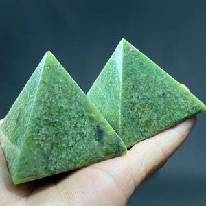 Puede incluir: Dos pirámides de jade verde, una ligeramente más grande que la otra, con una superficie rugosa y texturizada.