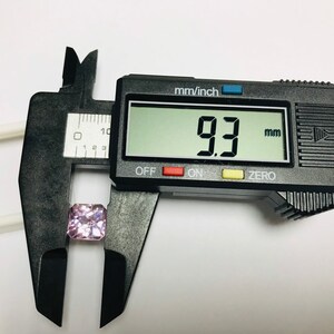 May include: A close-up of a digital caliper measuring a pink gemstone. The caliper reads 9.3 mm.