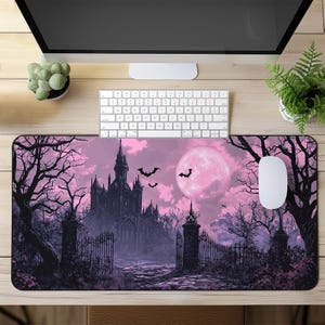 Puede incluir: Una alfombrilla de ratón morada y negra con un tema de Halloween espeluznante. El diseño presenta un castillo oscuro con una puerta, murciélagos volando en el cielo y una luna llena.