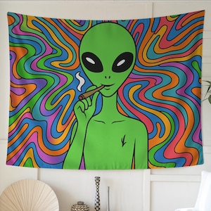 May include: A green alien with black oval eyes and a smile, smoking a rolled cigarette. The alien is set against a vibrant, psychedelic background of swirling orange, blue, green, and purple colors. The tapestry is a unique piece of art.