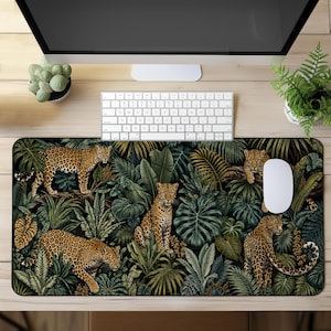 May include: A rectangular desk mat featuring a detailed jungle pattern with multiple leopards positioned among various green tropical leaves, ferns, and palm fronds. The design displays a dark, lush forest aesthetic with spotted big cats.