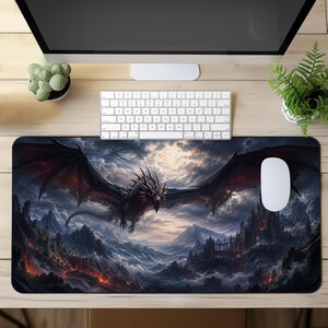 Könnte beinhalten: Eine rechteckige Schreibtischunterlage mit einer detaillierten Illustration eines schwarzen Drachen mit großen Flügeln, der über eine Berglandschaft mit Burg, glühender Lava und bewölktem Himmel fliegt. Die Unterlage liegt auf einem Holztisch mit Tastatur und Maus.