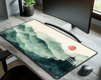 May include: A large, rectangular mouse pad with a green and white watercolor design of mountains and a red sun. The mouse pad is on a wooden desk with a computer monitor and a potted plant.