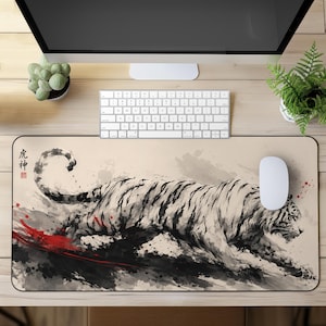 Puede incluir: Una alfombrilla de escritorio rectangular con una ilustración en estilo de tinta china en blanco y negro de un tigre en movimiento. El diseño incluye salpicaduras de pintura roja y caracteres kanji japoneses negros sobre fondo beige.