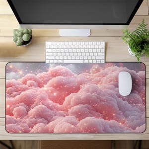 May include: A pink and white mouse mat with a sparkly cloud design. The mouse mat is on a wooden desk with a computer monitor, keyboard, and potted plants.