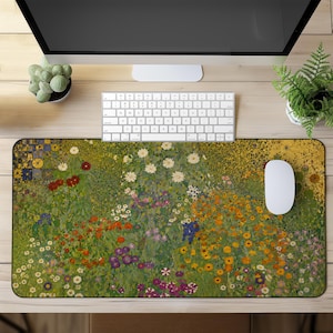 Op de afbeelding: Een rechthoekige bureaumat met een levendige, veelkleurige bloementuinprint met een dichte schikking van rode, oranje, gele, witte en paarse bloemen tegen een weelderige groene achtergrond, geplaatst op een houten bureauoppervlak.