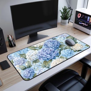 Peut inclure: Un tapis de souris floral bleu et blanc avec une souris d'ordinateur dessus. Le tapis de souris présente un motif d'hortensias à l'aquarelle.
