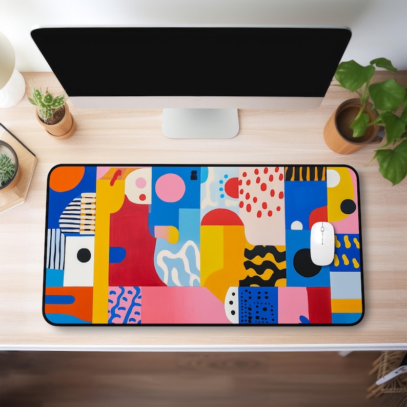 Op de afbeelding: Een muismat met een kleurrijk abstract ontwerp en een zwarte rand. Het ontwerp bevat geometrische vormen in tinten rood, geel, blauw, roze en zwart.
