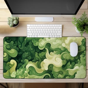 May include: Green and yellow abstract design mousepad with swirling patterns. The mousepad is on a wooden surface with a computer keyboard, a computer monitor, and two potted plants.