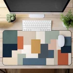Può includere: Un tappetino da scrivania rettangolare caratterizzato da un motivo geometrico di blocchi di colore solido nelle tonalità blu navy, arancione bruciato, giallo senape, verde salvia, crema e rosa tenue, disposti in una composizione moderna.